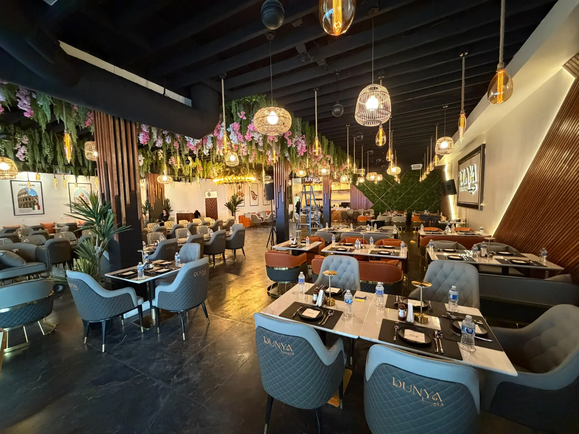 Warm, elegant DUNYA dining room with floral ceiling, pendant lights, and guests gathered around the table
