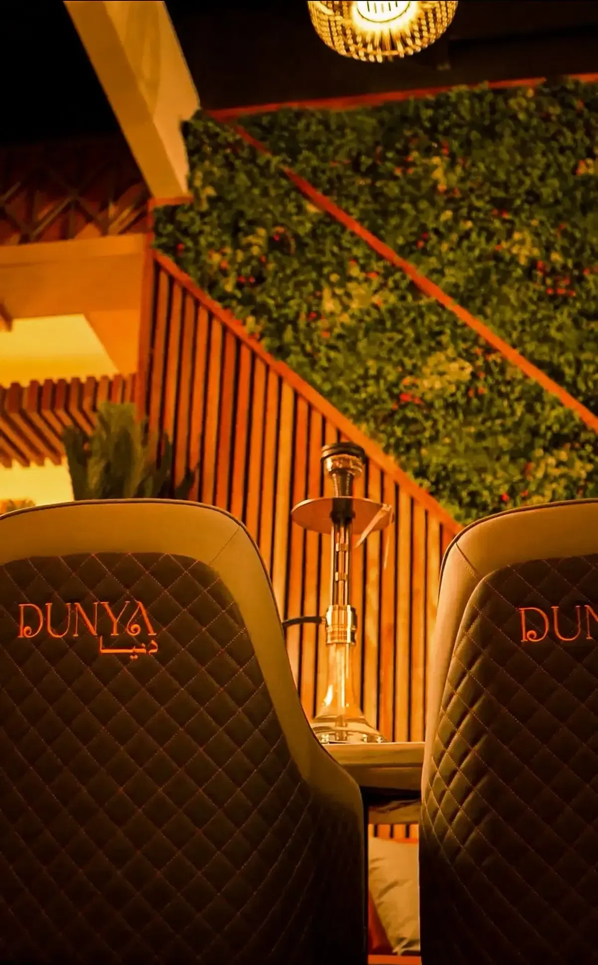 DUNYA lounge with branded leather seating, a hookah, and warm ambient lighting